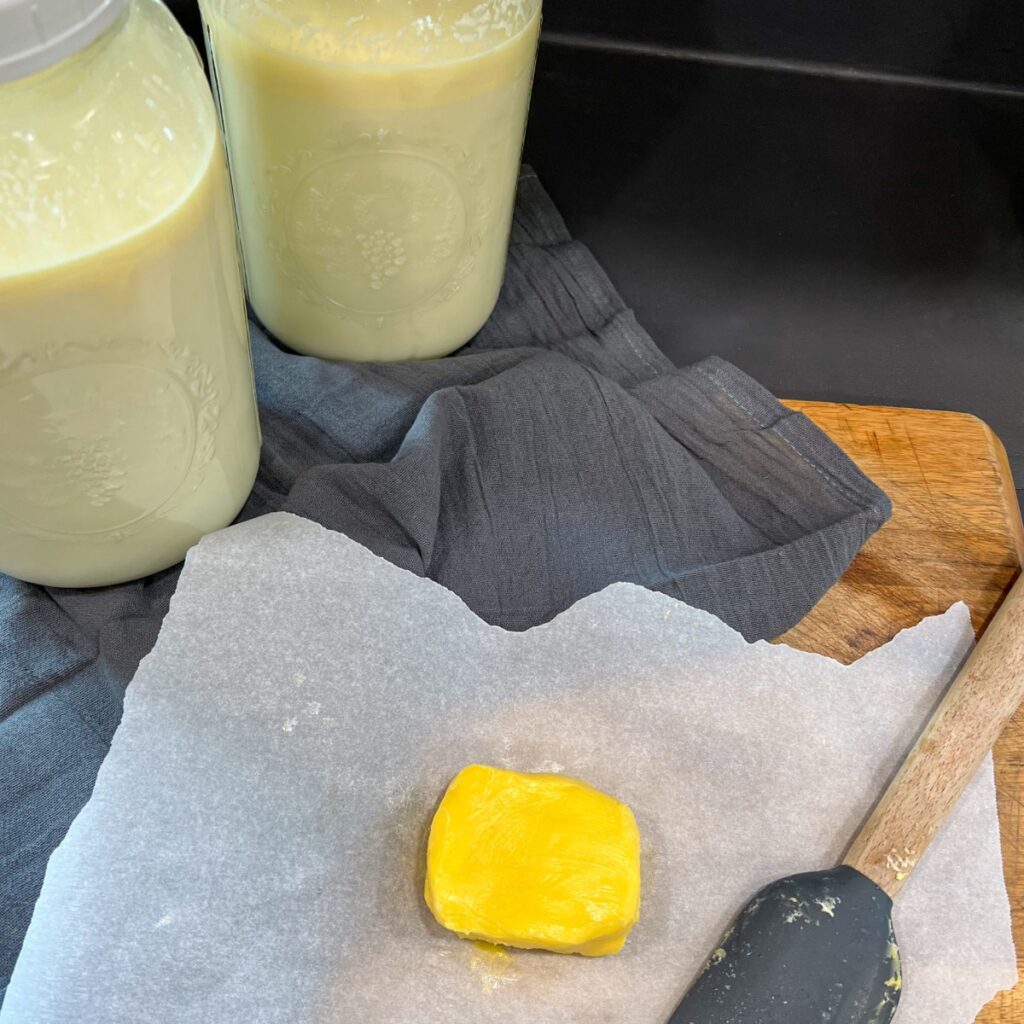 Butter on parchment paper next to raw milk and spatula 